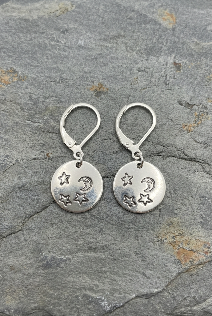 Flat lay of the moon and star earrings with closed leverback fittings on slate